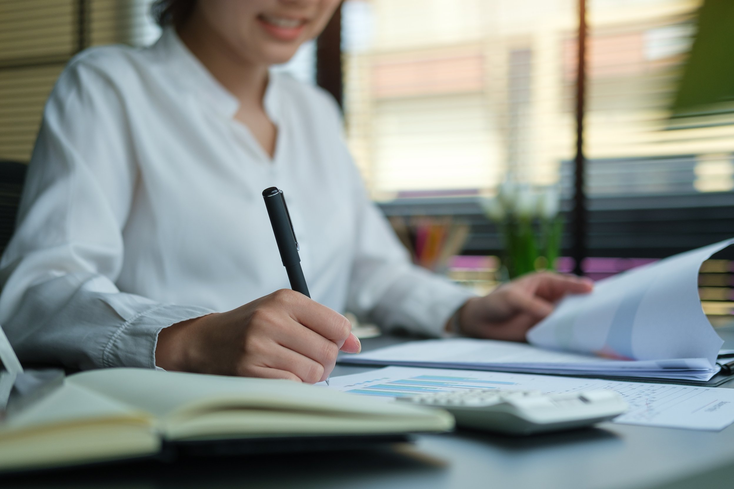 A young female administrative assistant making notes of working